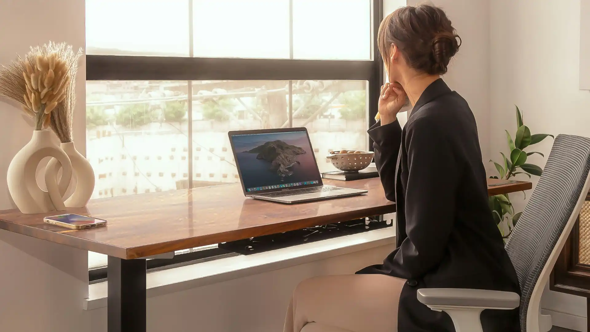 Woman looking out the window – productive day at work – health benefits of sit stand desk