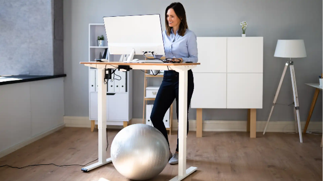 Woman using an electric standing desk in home office for good posture