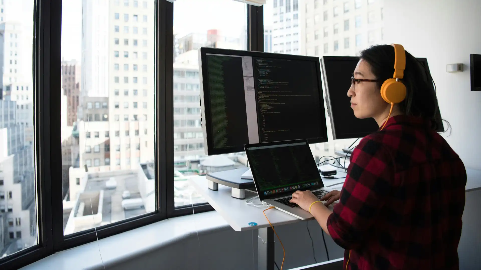 A woman working on a computer using a standing desk