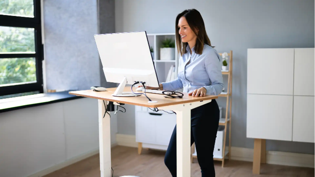 Person happily using a standing desk in office for good posture