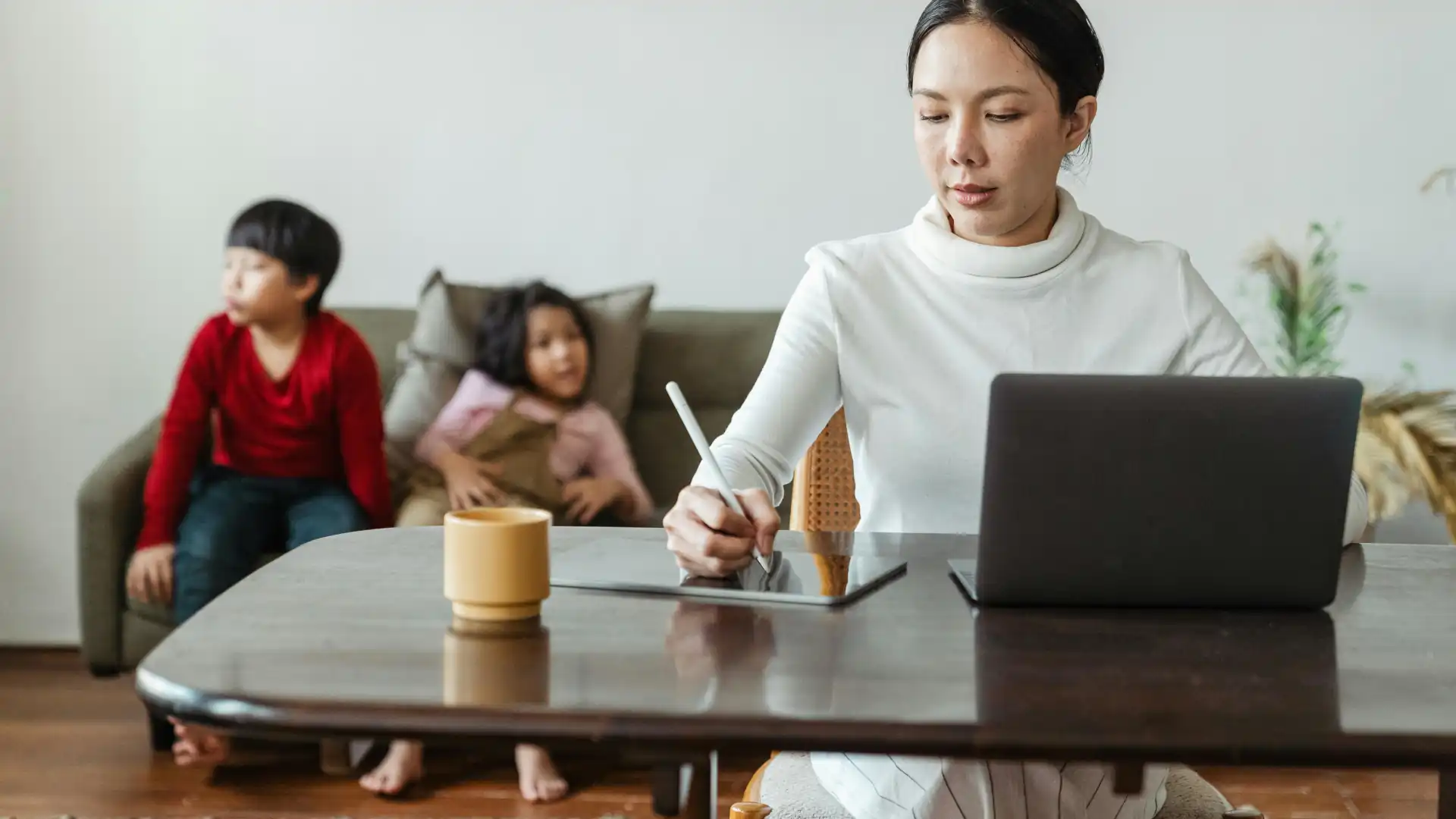 Woman using a trestle table for work with kids in the background